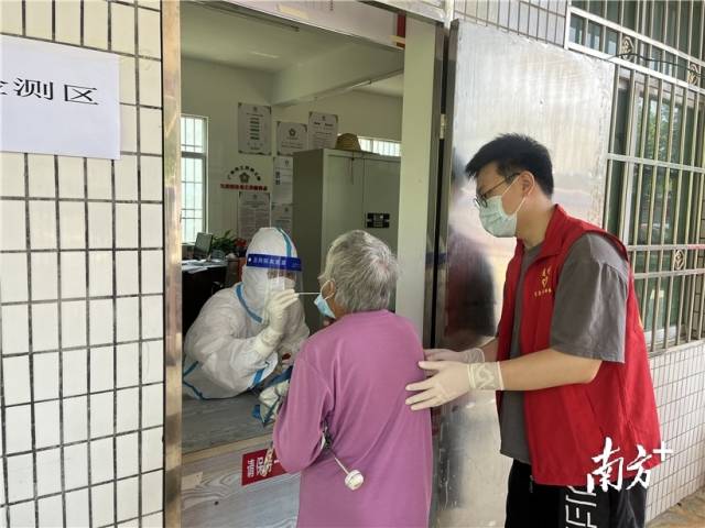 現(xiàn)場志愿者幫助行動(dòng)不便群眾接受核酸檢測。